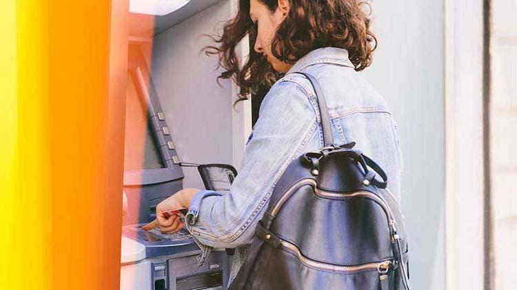 Woman easily accessing her 检查 account funds by using an ATM.