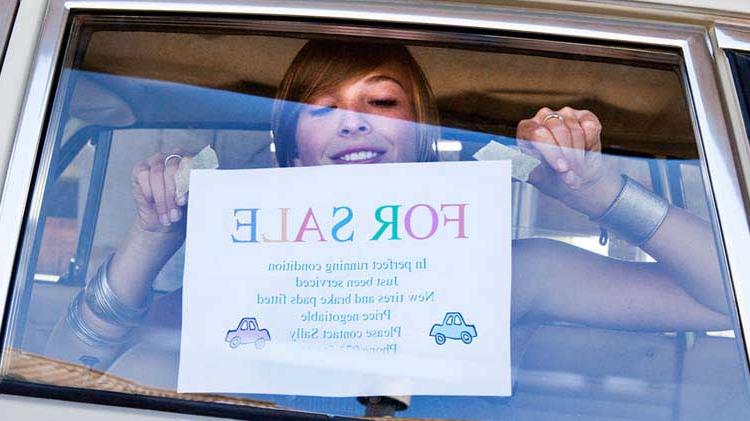 一名妇女在车窗上挂着自制的“出售”牌子