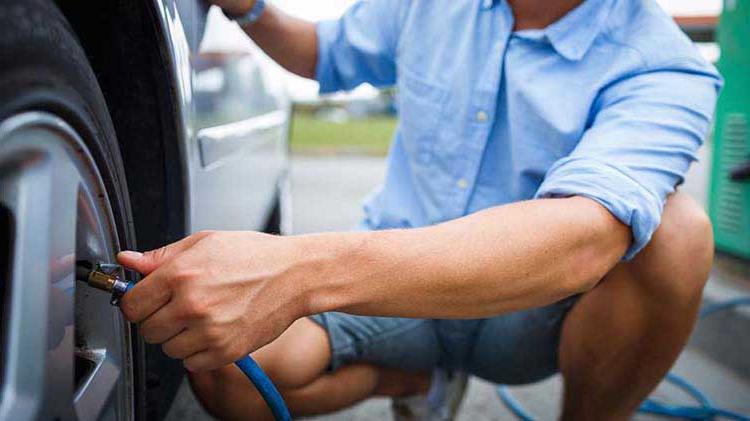 一个穿蓝衬衫的男人检查他的轮胎气压.